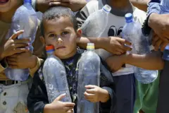 صورة أرشيفية لأطفال غزة يحملون عبوات فارغة ويسعون لتعبئة مياه الشرب