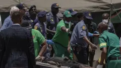 Un minero es llevado en una camilla por rescatistas tras ser rescatado de una mina ilegal