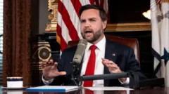 Вице-президент Джей Ди Вэнс, в костюме с красным галстуком ведет выпуск The Charlie Kirk Show, сидя за столом в Белом доме 