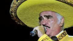 Vicente Fernández vestido de amarillo con un micrófono