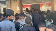 العشرات (بينهم نساء وأطفال) يصطفون أمام مخبز في دير البلح جنوب قطاع غزة