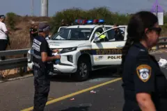 أفراد من أجهزة الأمن والطوارئ الإسرائيلية يتفقدون سيارة شرطة متضررة في موقع إطلاق نار على تقاطع يافنه، بالقرب من مدينة أسدود جنوب إسرائيل في 15 أكتوبر 2024