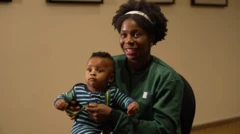 Foto of Sarah Ogoke - Taylor wey wear Nigeria great track top wey carry di Nigeria flag. She hold her son for her lap as she wrap her gold medal for in neck.