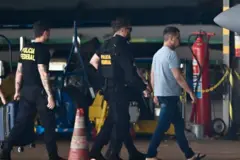 Silvinei Vasques, ex-diretor da Polícia Rodoviária Federal do Brasil, chega ao Aeroporto Internacional Juscelino Kubitschek escoltado por agentes da Polícia Federal em Brasília, em 27 de dezembro de 2025, após ser entregue pelas autoridades paraguaias.