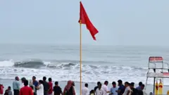 শুক্রবার কক্সবাজারের সাগর তীরে মানুষের ভিড়। লাল পতাকা তুলে সাগরে না নামতে হুঁশিয়ার করে দেয়া হচ্ছে পর্যটকদের। 