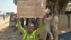 A child displays a placard written 'we are in critical condition' in one of the communities ravaged by bandit attacks in kaduna State, Nigeria.