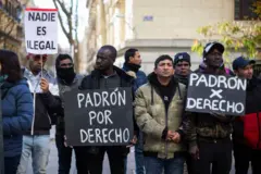 Dos inmigrantes sostienen carteles que dicen "Registro por derecho" en español, durante una manifestación frente al Ayuntamiento de Madrid.