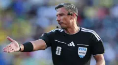 El árbitro Slavko Vinčić levanta su brazo derecho mientras dirige un partido