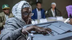 Otu nwaanyị yi uwe isi awọ na akwa isi ma yiri ugogbe anya na-atụ vootu n'Addis Ababa