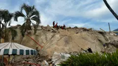 Escombros sobre el conjunto residencial Caribe, en la parroquia Caraballeda, estado La Guaira. En la cima de la pila de escombros se ve un pequeño grupo de rescatistas.