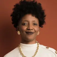 A pesquisadora Fernanda Rodrigues em retrato, usando um colar dourado e camisa branca com botões