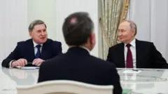 Троє чоловіків у костюмах сидять за столом. Це - Володимир Путін, Юрій Ушаков і Стів Віткофф