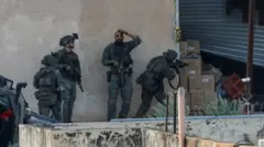 Las tropas israelíes en Yenin toman posición detrás de un muro frente a la puerta de un garaje antes de que los palestinos salgan de él.