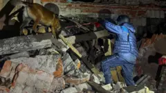 спасатель и собака ищут людей под обломками разрушенного здания