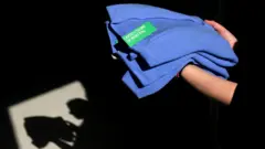 Chica sosteniendo suéters de Benetton