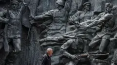 رجل يمر أمام نحت بارز من زمن الاتحاد السوفياتي في المتحف الوطني لتاريخ أوكرانيا في الحرب العالمية الثانية في كييف