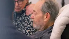 Homem idoso sentado ao lado de familiares