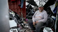 Homem sentado em meio a sucata