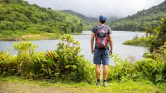 배낭을 메고 눈앞의 강과 산을 바라보는 한 남성