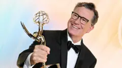 Stephen Colbert ergue seu Emmy, enquanto se dirige a uma festa da premiação no domingo passado, 14 de setembro de 2025