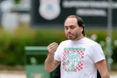 Carlos Bolsonaro saindo da Superintendência da Polícia Federal, com expressão de preocupação e uma camiseta das Tartarugas Ninja