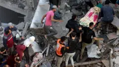 رجال الدفاع المدني ومواطنون فلسطينيون ينتشلون جثة من بين حطام أحد المنازل في مخيم رفح التي دمرها تجدد القصف الإسرائيلي على قطاع غزة
