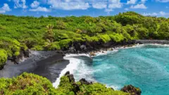 The famous black sand beach and spectacular coastal view in Maui, on the road to Hana, on a sunny day.