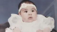 Jessica López de pequeña, vestida con un vestido blanco y una diadema.