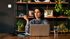 سيدة تجلس أمام جهاز الحاسوب وتفكر 