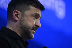 Zelenskiy profilden görünüyor. Sadece kafasını görüyoruz, arkada mavi bir fon var.