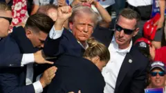 O candidato republicano Donald Trump foi visto com sangue no rosto, cercado por agentes do Serviço Secreto, enquanto era retirado do palco em um evento de campanha na Butler Farm Show Inc., em Butler, Pensilvânia, em 13 de julho de 2024
