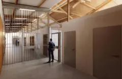 Imagem mostrando a entrada de várias celas em prisão, com um guarda de costas