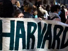 Manifestantes com faixa com o nome da Universidade americana Harvard