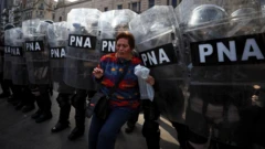Uma mulher na frente de vários policiais com escudos