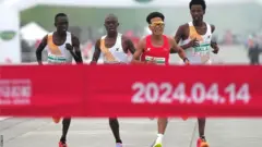 ハーフマラソンのゴールに先頭で入る中国の何傑選手と、そのすぐ後ろに続くケニアの3選手続いた