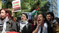 أشخاص يحملون لافتات وأعلام خلال احتجاج لدعم الفلسطينيين في غزة
