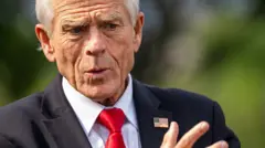 Peter Navarro, umujyanama mukuru ku bucuruzi n'inganda wo mu biro bya perezida w'Amerika (White House). Yambaye ikoti ry'umukara, ishati y'umweru na karuvati itukura. Arimo kuganira n'abanyamakuru i Washington DC, ku itariki ya 6 Kanama (8) mu mwaka wa 2025. 