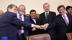 O Ministro das Relações Exteriores do Brasil, Celso Amorim, o Presidente Luiz Inácio Lula da Silva, o Presidente iraniano, Mahmoud Ahmadinejad, o Primeiro-Ministro turco, Recep Tayyip Erdogan, e o Ministro das Relações Exteriores da Turquia, Ahmet Davutoglu, de mãos dadas
