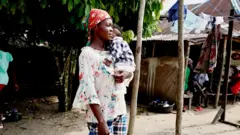 A woman carrying a baby