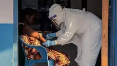 Врач берет пробу крови у больной Эболой