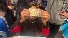 Baraa Abu Aoun repairs worn-out banknotes circulating in the streets of Gaza.