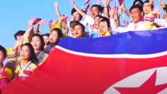 Un grupo de personas agitan una gran bandera de Corea del Norte en uno de los momentos del video. 