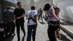 Pessoas correm por uma rua em meio à fumaça após os ataques israelenses ao Irã, em Teerã, Irã, 15 de junho