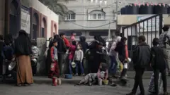 فلسطينيون نازحون في رفح جنوب قطاع غزة، يتجمعون لجمع الطعام الذي تبرعت به مجموعة خيرية قبل الإفطار، في شهر رمضان، 14 مارس/آذار 2024.