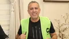 Haluk levent'in üzerinde fosforlu iş yeleği var, üzerinde ahbap derneğinin logosu bulunuyor. 
