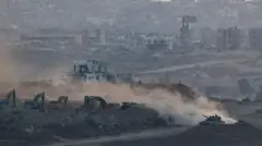 Israeli tank manoeuvres near heavy machinery, with a view of destruction in North Gaza, in the background, as seen from the Israeli side of the border, July 17, 2025. 