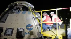 Dos trabajadores de la NASA inspeccionan la nave