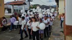Un grupo de niños y niñas con camisetas blancas y globos blancos