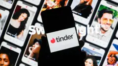 Tinder uygulaması ön tarafta açık ve arka tarafta profil sahibi kişilerin fotoğrafları