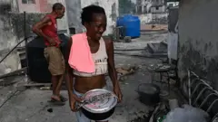 Mulher carrega uma panela durante um apagão em Havana